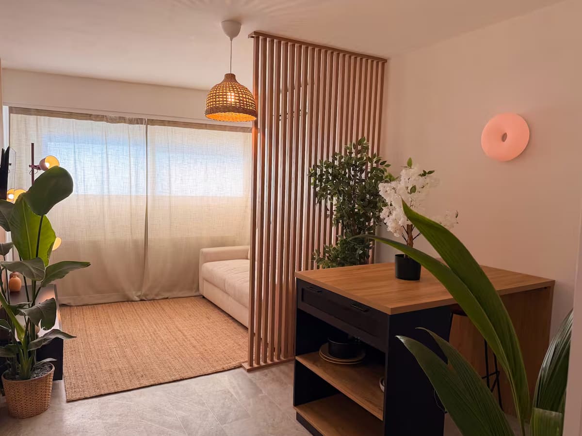 Séjour du studio du boulevard Carnot, au Cannet : claustra en bois, canapé et bureau